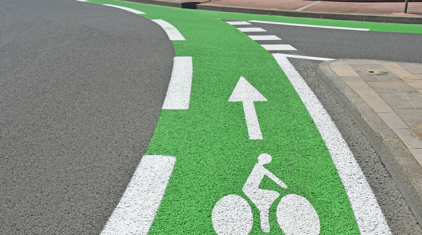 Piste cyclable protégée par séparateur physique en centre-ville français avec marquage au sol et signalisation vélo